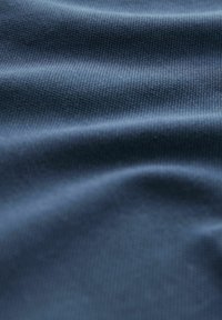 Marineblåt stof med en tekstureret overflade, der viser bløde folder og et glat udseende, sandsynligvis lavet af et blandet syntetisk materiale.