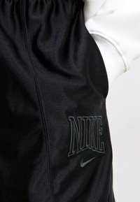 Black Nike shorts with an elastic waistband. Features embossed Nike logo and subtle texture, emphasizing a smooth fabric finish.