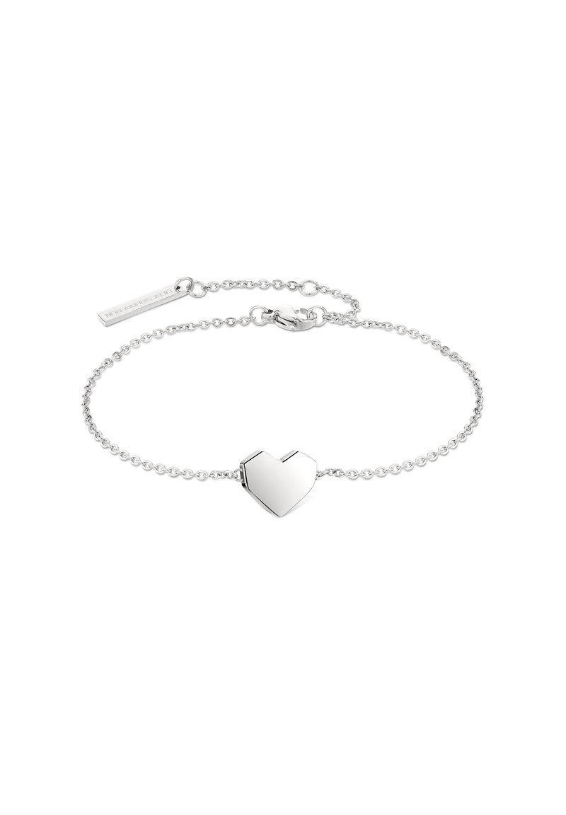 Silver chain bracelet featuring a heart-shaped charm with a polished finish and a small rectangular tag, adjustable length with a clasp.