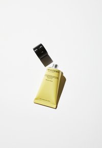 Gul tub av solskydd med svart kork, med en strukturerad yta, märkt med produktinformation och SPF 30.
