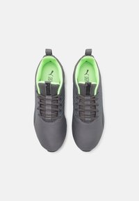Grå sportskor med ovandel i nät, kontrasterande neongrön foder och platta snören. Har en dragflik vid hälen för enkel påtagning.