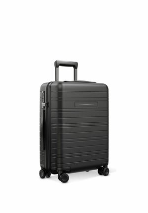 Black hard-shell suitcase with horizontal grooves, telescopic handle extended, side handle, and four spinner wheels on white background.