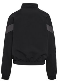 Svart jacka med hög krage, elastisk nederkant och långa ärmar med grå ränder över axlarna och sidorna. Slät, matt textur.