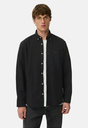 Zwarte button-up shirt met een kraag, voorzien van een enkele borstzak en contrasterende knopen, gedragen over een wit t-shirt. Geverfd stof.
