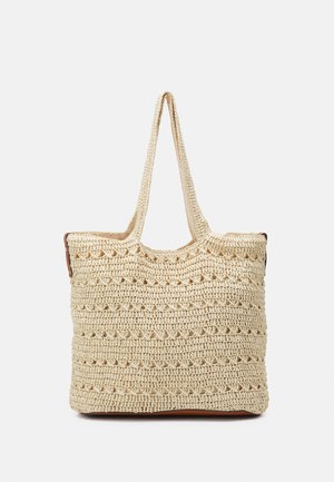 Bolso tote de paja trenzada en beige natural con dos asas largas y abertura superior. Presenta un patrón texturizado con detalles recortados.