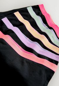 Cinq ensembles de sous-vêtements noirs avec des ceintures pastel en rose, violet, jaune, vert et rouge, chacun portant l’étiquette "NEXT".