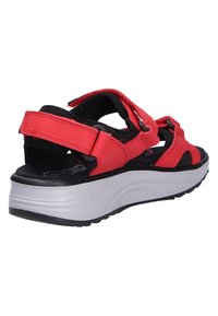 Red sandal featuring synthetic straps, adjustable closures, and a cushioned black footbed. Outsole is thick and textured for grip.