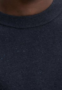 Dunkelblauer Pullover mit strukturiertem Strick, ausgestattet mit einem klassischen Rundhalsausschnitt und subtilen Sprenkeln in hellblau im gesamten Stoff.