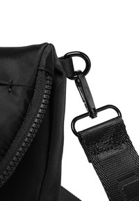 Černá nylonová taška s zipem, tkaným popruhem s klipem a hladkým povrchem. Design obsahuje zaoblené hrany.