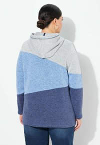 Mikina s kapucí s barevným blokováním v šedé, světle modré a tmavě modré barvě. Vyrobena z texturované látky, má dlouhé rukávy a uvolněný střih.