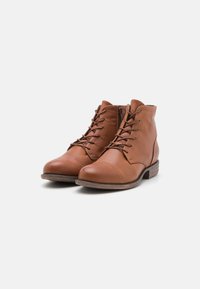 Brune lær ankle boots med en glat tekstur, der har snøring fortil og lynlås i siden. Lav stablet hæl og rund tå design.