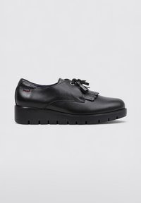 Zapato de cuero negro con un acabado suave, detalle decorativo de flecos y una suela negra gruesa con un patrón de relieve para mayor agarre.