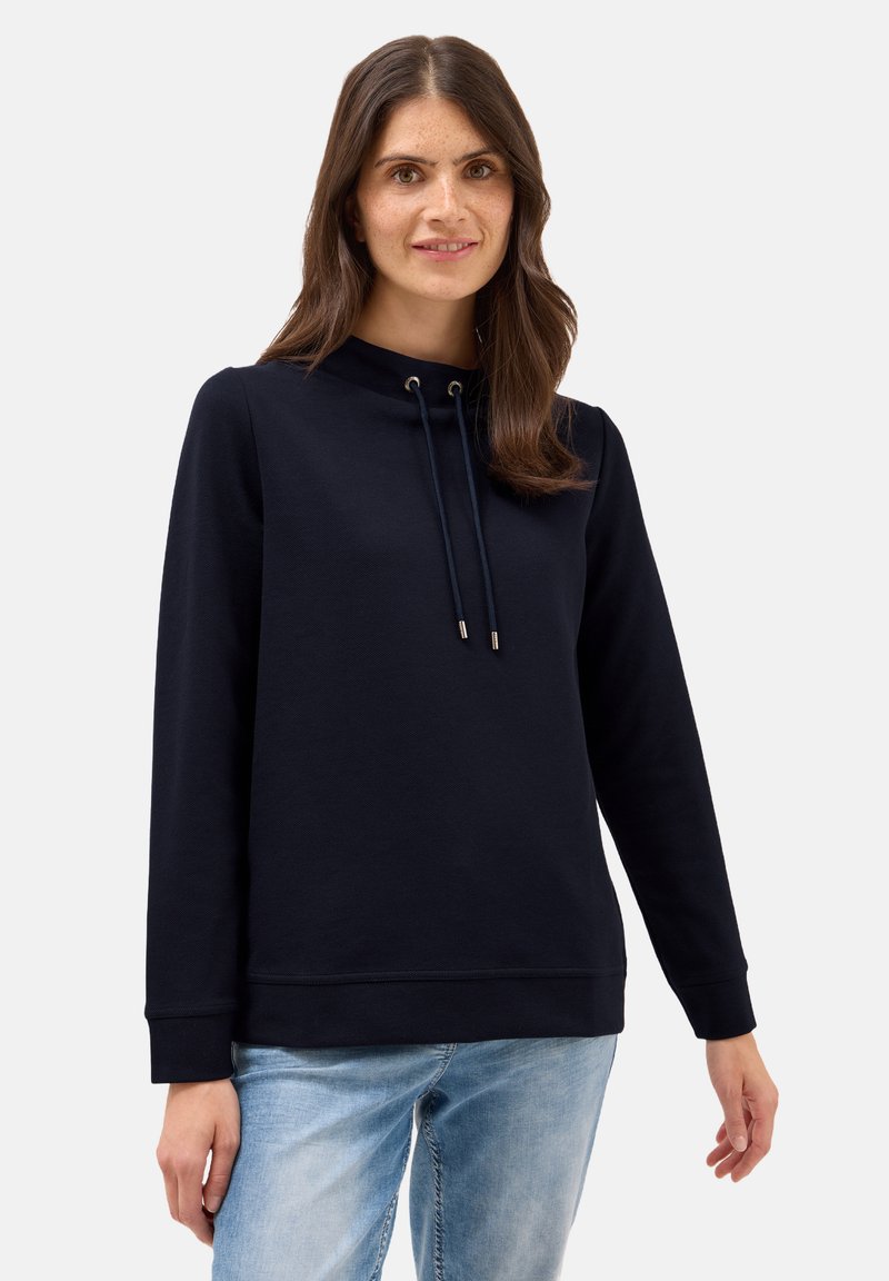 Mörkblå sweatshirt med hög krage, snörning, långa ärmar, ribbade mudd och en mjuk textur, kombinerad med ljusblå jeans.