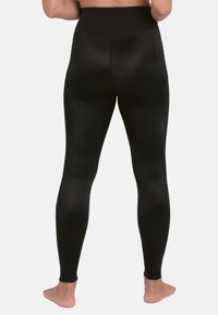 Schwarze Leggings mit hohem Bund, die ein strukturiertes Muster aufweisen. Das Material ist glatt und figurbetont und reicht bis zu den Knöcheln.