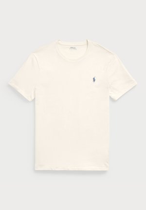 T-shirt en coton couleur crème avec un col rond et des manches courtes. Présente un petit logo bleu brodé sur le côté gauche de la poitrine.