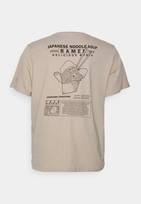 Beige t-shirt featuring a graphic print of ramen in a takeout box with chopsticks, accompanied by text for Yokohama Chinatown restaurant hours.