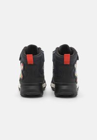 Črne visokotopne čevlje s trdim gumijastim podplatom, tekstilnim zgornjim delom, rdečo zanko na peti in barvitimi karakterji na straneh.