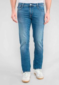 Jean en denim bleu à coupe slim, doté d'un design classique à cinq poches, d'une légère décoloration et d'une fermeture à bouton au niveau de la taille.