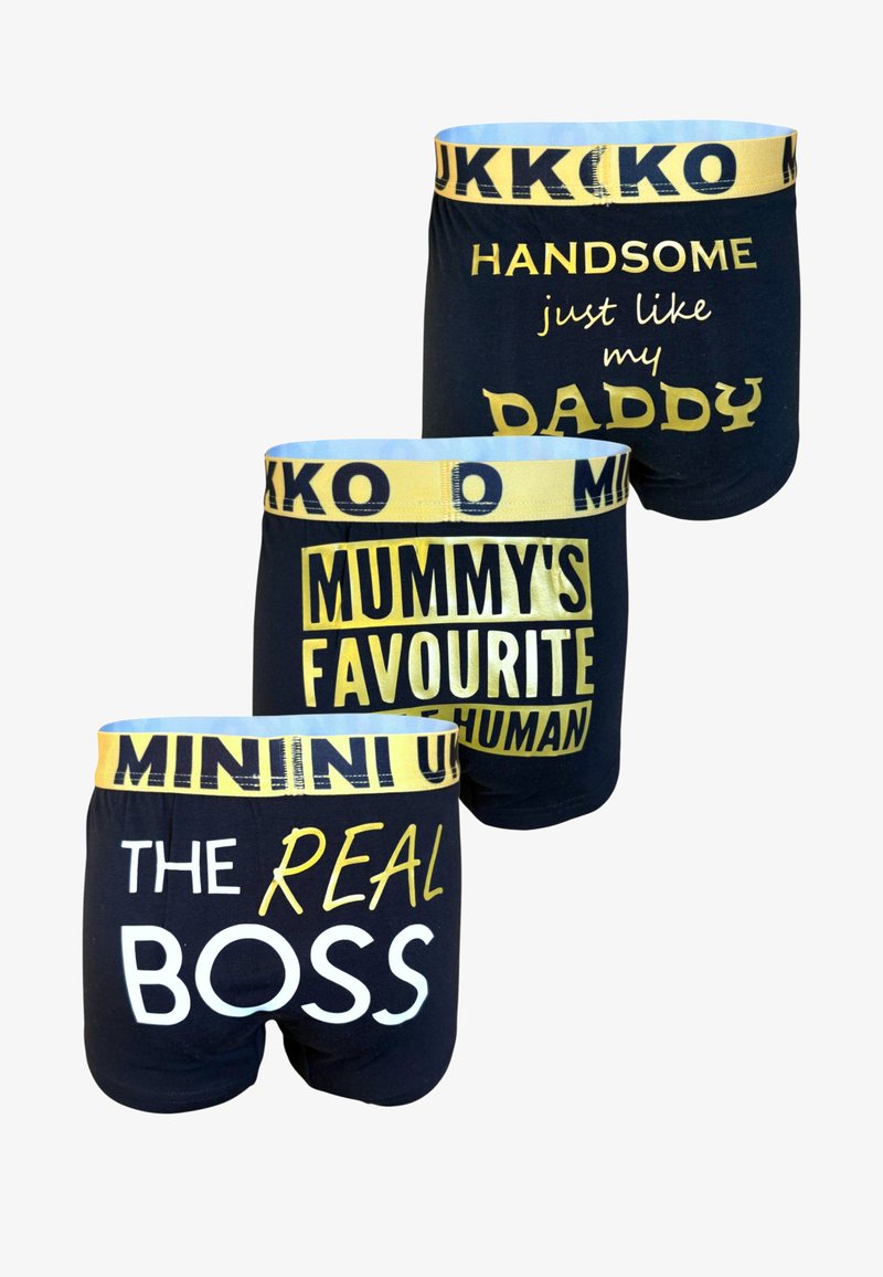 Tre par svarta bomullskalsonger med gula elastiska midjeband, varje med olika tryckt text i vitt och gult.