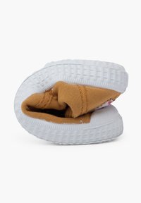 Chaussure avec une semelle en caoutchouc blanc et un dessus en tissu beige plié. Présente une semelle texturée et des accents cousus. Design compact pour un rangement facile.