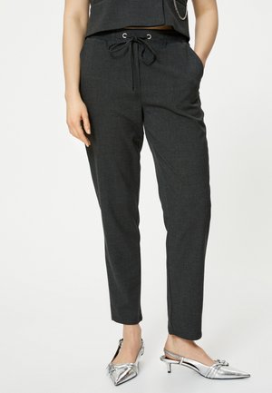 Mørkegrå bukser med snoretræk i taljen, tætsiddende pasform og sidelommer, samt sølvfarvede slingback hæle med spidse tæer.
