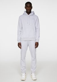 Ljusgrå hoodie med känguruficka, långa ärmar och snörning i huvan, ihop med matchande träningsbyxor. Tyg av bomullsmix.