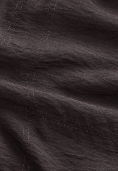 Tissu brun foncé avec des coutures visibles formant des coutures croisées et de subtiles rides sur toute la surface.