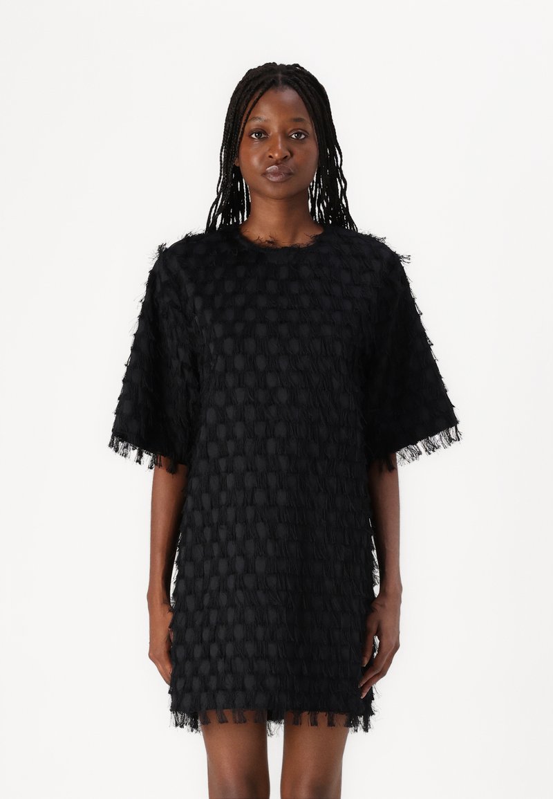 Robe noire avec des motifs texturés en relief, manches courtes et ourlet frangé. Fabriquée en tissu léger, avec un col rond.