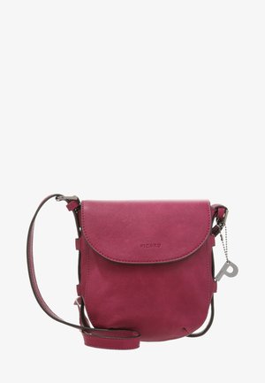 Petit sac bandoulière en cuir rose avec rabat, sangle ajustable et charm métallique de la marque accroché à une chaîne sur le côté.
