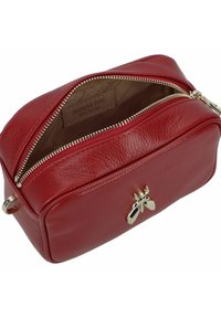 Rode leren cosmetische tas met ritssluiting, voorzien van gouden beslag en een decoratieve bij-accent aan de voorkant. Binnenin een zichtbaar merklabel.