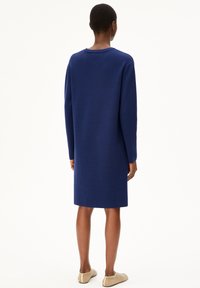 Robe à manches longues, longueur genou, en tissu tricoté bleu marine uni, présentant un col rond et une silhouette droite simple.