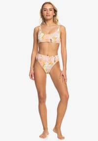 Bikini deux pièces avec un motif floral multicolore dans des teintes pastel, décolleté carré et bas taille haute. Texture de tissu lisse.