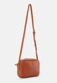 Piccola borsa a tracolla rettangolare in pelle marrone con una lunga tracolla regolabile e un compartimento principale con cerniera.