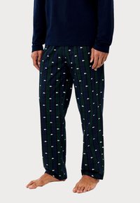 Bavlněné pyžamové kalhoty s tmavě modrým a zeleným kostkovaným vzorem, zdobené bílými logy. Volný střih s elastickým pasem, stažené na kotnících.