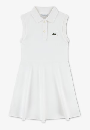 Abito bianco senza maniche con colletto polo, dotato di una patta con bottoni e logo Lacoste verde sul petto. Tessuto liscio ed elastico.