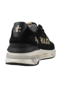 Schwarzer Sneaker aus Wildleder mit Mesh-Seiten, auffälligem gelbem Text am Obermaterial und einer dicken weißen Zwischensohle mit schwarzen Gummiaccenten.