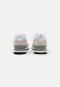 Světle šedé semišové a bílé síťové sportovní boty s černou gumovou podrážkou; logo "new balance" na patě v šedé barvě; nízkoprofilový design.