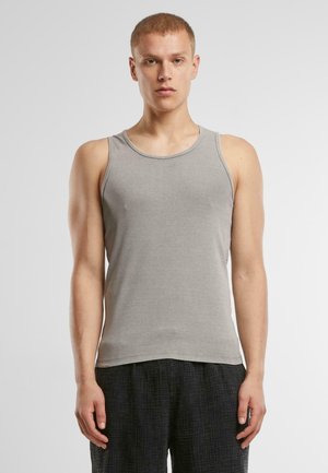 Graues ärmelloses Tanktop aus weichem Stoff, mit einem runden Ausschnitt und schlanker Passform. Getragen mit strukturierten schwarzen Shorts.