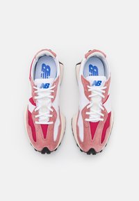 Les baskets présentent un mélange de suède rose et de mesh blanc, une semelle en caoutchouc noire, un bout arrondi, et des lacets plats avec un logo bleu sur la semelle intérieure.