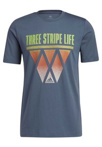 Šedé tričko s krátkým rukávem vyrobené z bavlny, s grafickým designem a textem "THREE STRIPE LIFE" a geometrickým vzorem v oranžové a žluté barvě.
