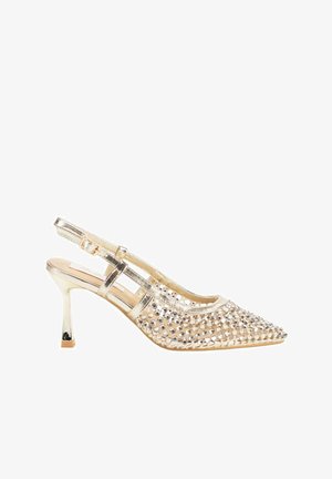 Tacón slingback dorado con punta afilada, adornado con detalles de pedrería. Presenta una superficie metálica brillante y un diseño de tacón delgado.