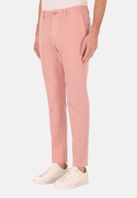 Roze katoenen broek van een blend met een smal toelopende pasvorm, sluiting met een knoop aan de voorkant en zijzakken, gecombineerd met witte sneakers.