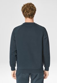 Felpa blu navy, misto cotone, colletto tondo, maniche lunghe raglan, polsini e fondo a costine, texture liscia, design minimalista.