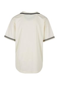 Kremowa koszula z krótkim rękawem, z zaokrąglonym dołem, ozdobiona czarną lamówką na rękawach i szwach barkowych, wykonana z gładkiej, lekkiej tkaniny.