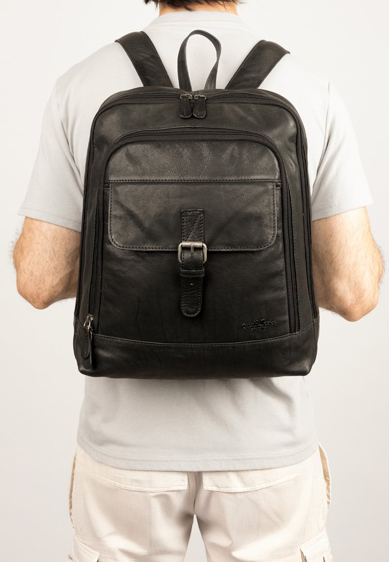 Schwarzer Leder-Rucksack mit verstellbaren Trägern, Fronttasche mit Schnalle, Seitenreißverschluss und texturiertem Finish. Eignet sich für den täglichen Gebrauch.