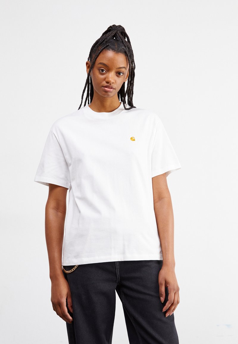 Witte katoen T-shirt met een ronde hals, korte mouwen en een klein, geel logo op de borst. Gekocht bij donkere jeans met een kettingdetail.