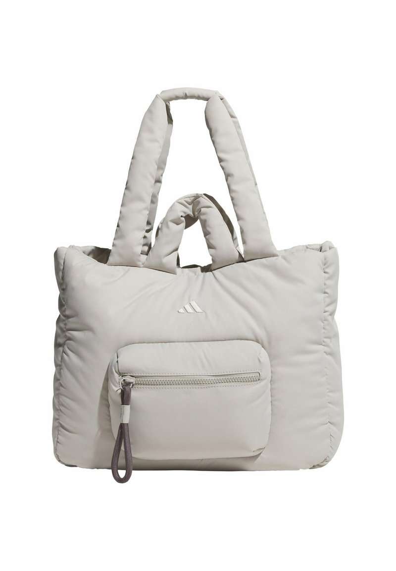 Puffy light gray tote bag with dual elongated straps, featuring a front zip pocket and subtle logo detailing. Soft, quilted texture.