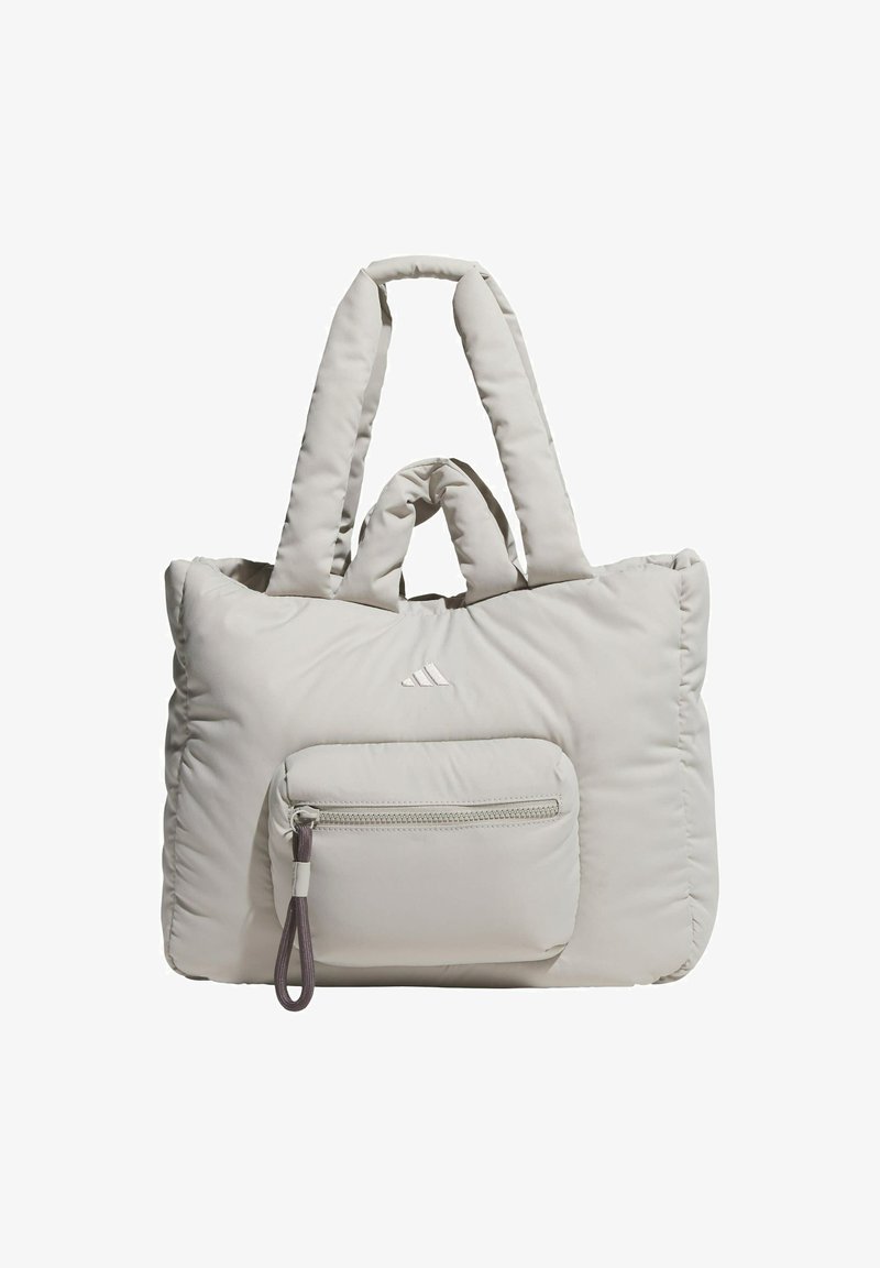 Puffy light gray tote bag with dual elongated straps, featuring a front zip pocket and subtle logo detailing. Soft, quilted texture.