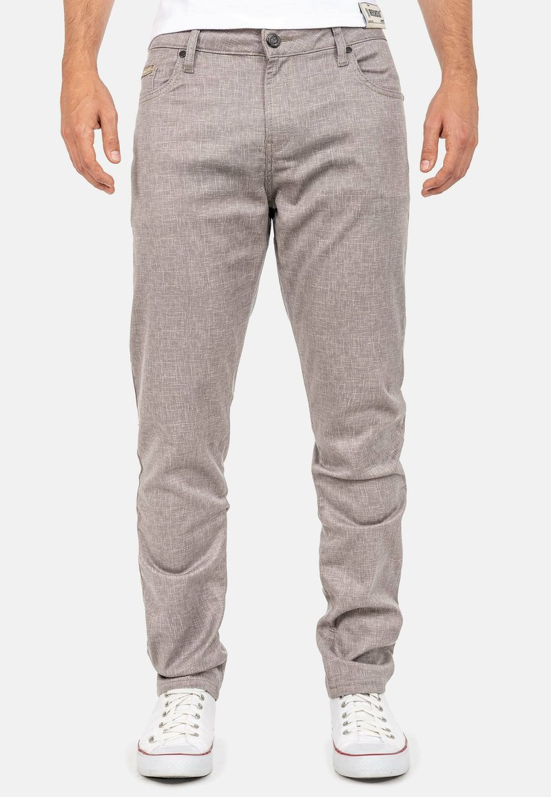 Lichtgrijze chino's met een gestructureerd patroon, slim fit, vijf zakken, knoopsluiting en omgeslagen pijpen, gecombineerd met witte sneakers.