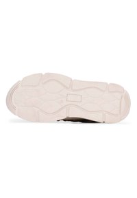 Zwarte sneaker met een gestructureerde bovenzijde, voorzien van een witte rubberen loopzool met een golvend patroon, wat grip en duurzaamheid biedt.